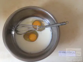 Шаг 2: Влейте в миску молоко, добавьте 2 яйца и взбейте венчиком.