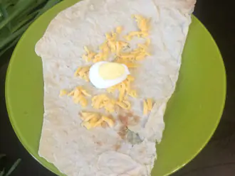 Шаг 3: Лаваш поделите на три части . Потрите сыр на крупной терке и порежте вареные яйца. Полученную начинку выложите на середину лаваша.