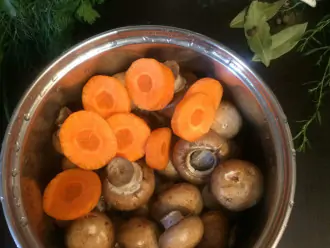 Шаг 2: Хорошенько промойте грибы, очистите и нарежьте кружочками морковь. Уложите в небольшую кастрюлю (примерно на 2 литра). 