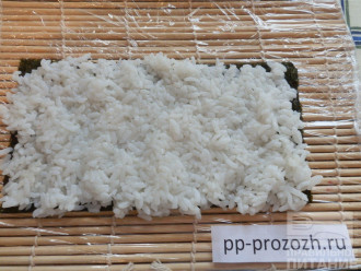 Шаг 3: Руки смочите в воде, возьмите рис и накладывайте его на нори растягивающими движениями. Если вы правильно приготовите рис, то будет легко получаться.