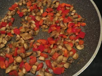 Шаг 3: В разогретую с маслом сковороду отправьте сначала лук, через 10 минут добавьте грибы. Все обжарьте на среднем огне до золотистого цвета. Затем добавьте нарезанный перец и готовьте пока не стянет мягким.