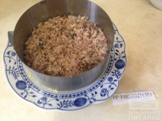 Шаг 4: Достаньте сардину из банок на тарелку и вилкой измельчите ее. Выложите в салат и слегка уплотните. Сверху насыпьте слой маринованного лука.