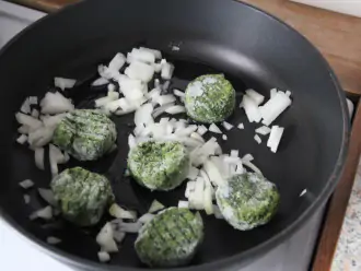 Шаг 3: Растопите ложку масла в сковороде и обжарьте лук с замороженным шпинатом 7 минут.