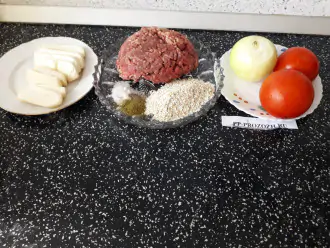 Шаг 1: Подготовьте компоненты котлет: фарш, овсяную крупу, лук, помидоры, сыр, соль и специи.