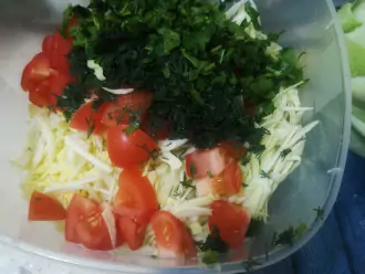 Шаг 5: К капусте добавьте нарезанную зелень и помидор.