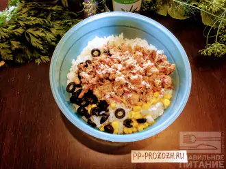 Шаг 4: Сардину измельчите вилкой. Возьмите глубокую тарелку и высыпьте рис, маслины, консервированную кукурузу (примерно 2 столовые ложки) и сардину.
