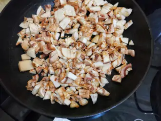 Шаг 5: Нарежьте шампиньоны, обжарьте 10 минут. К ним добавьте нарезанный мелко чеснок.