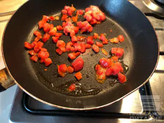 Шаг 2: На разогретую сковороду с чайной ложкой оливкового масла выложите замороженные помидоры (или нарежьте кусочками свежие). Обжарьте 3 минуты на среднем огне.