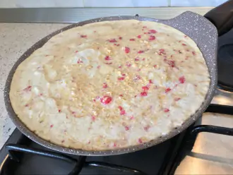 Шаг 4: На разогретую сковороду добавьте масло и вылейте тесто, слегка разровняйте лопаткой.