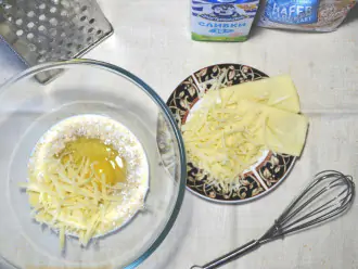 Шаг 3: Натрите сыр на крупной терке, половину добавьте в яично-овсяную смесь и тщательно размешайте.