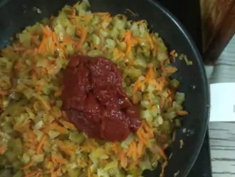 Шаг 6: В сковороде пассеруйте лук и морковь, затем добавьте соленые огурцы и томатную пасту.