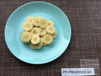 Шаг 2: Банан нарежьте кружочками и выложите в тарелку первым слоем.