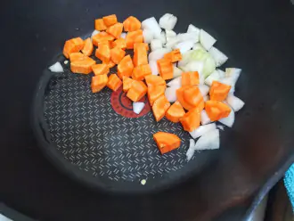 Шаг 3: К луку добавьте также нарезанную морковь и чеснок.