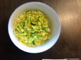 Шаг 4: Огурец помойте и нарежьте соломкой. Возьмите глубокую тарелку и высыпьте в неё нарезанные овощи.