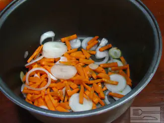 Шаг 2: Порежьте лук кольцами, морковь мелкими брусочками. Положите овощи в мультиварку, добавив немного растительного масла. Готовьте овощи на режиме "Обжарка" в течение 3 минут.