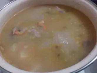 Шаг 7: Добавьте в суп лук и морковь и готовьте ещё 7-10 минут при слабом кипении. За пять минут до готовности попробуйте суп, досолите по необходимости, добавьте лавровый лист и молотый перец.