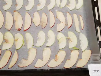 Шаг 4: Предварительно разогрейте духовку до 110 градусов. Расстелите на противень пергаментную бумагу и выложите дольки яблок. Я запекаю одновременно на двух противнях.