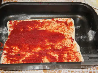 Шаг 4: Раскатайте пласт теста, смажьте томатной пастой, посыпьте отрубями, чесноком.