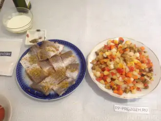 Шаг 2: Рыбу посолите, посыпьте приправой для рыбы и оставьте мариноваться. Замороженные овощи высыпьте в тарелку, чтобы немного разморозились.