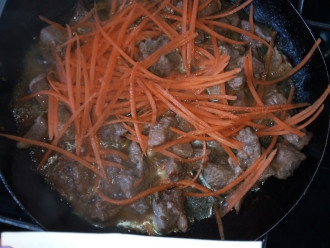 Шаг 5: За 10 минут до готовности мяса, добавьте в сковороду морковь.