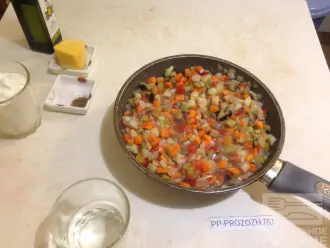 Шаг 4: На антипригарную сковороду  налейте 2 столовые ложки оливкового масла, поставьте на плиту. Выложите порезанный лук, овощи, добавьте полстакана воды и тушите 15-20 минут. 