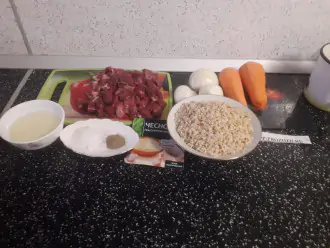 Шаг 1: Подготовьте все компоненты блюда: мясо, рис бурый, лук, морковь, масло, соль, чеснок и перец. Хорошо промойте бурый рис, залейте кипятком и оставьте на 3 часа. На фото промытый и замоченный рис