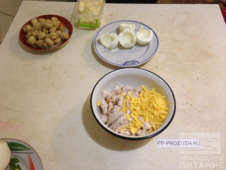 Шаг 2: Филе курицы порежьте, выложите в подходящую посуду. 
Отделите желтки от белков, потрите желтки на терке и добавьте к курице. 
Добавьте пару ложек майонеза и перемешайте. Разделите на две равные части.