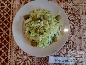 Шаг 4: Теперь соберите салат: смешайте капусту с огурцом  и выложите на тарелку, сверху положите оливки.