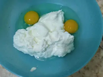 Шаг 2: В миску выложите творог и добавьте яйца. 