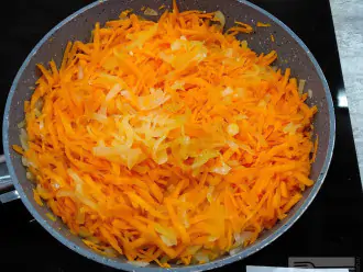 Шаг 3: Морковь почистите и натрите на крупной терке. Выложите к луку. Спассеруйте до мягкости. Остудите.