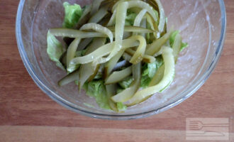 Шаг 6: Аккуратно порвите на кусочки листья салата и положите в отдельную тарелку, смешайте с заправкой, добавьте огурцы.